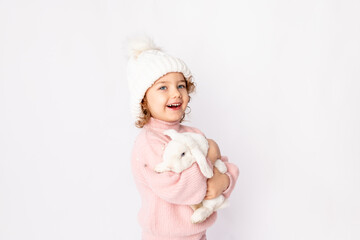 a little girl in winter clothes holds a rabbit on a white background. New year's concept, space for text