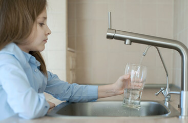 Child is pouring water from filter tap. Kitchen faucet. Quenches thirst. Filter system or osmosis,...