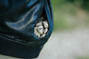 A pocket full of stones for a child in a black jacket, collected outdoors