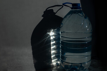 A plastic bottle with a shadow on a white background. Contrast image with deep shadows.