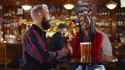 Portrait of romantic diverse couple holding hands on date in pub