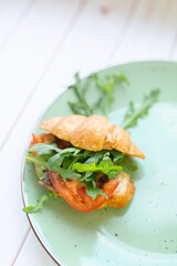 Croissant with rocket salad and vegetables on a ceramic dish on a wooden table