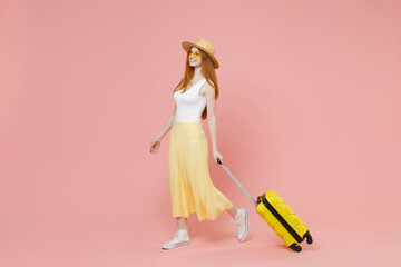 Full length body traveler tourist woman in summer clothes hat glasses walk with suitcase valise isolated on pastel pink background Passenger travel abroad weekends getaway Air flight journey concept.