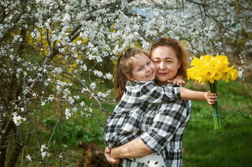 Fototapeta premium Portrait of mother and daughter with a bouquet of daffodils. Family on a spring walk
