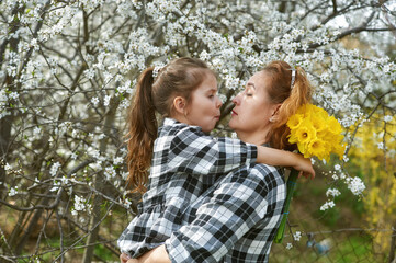 Portrait of mother and daughter with a bouquet of daffodils. Family on a spring walk