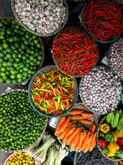 Fresh vegetables for sale at street food market in the old town of Hanoi, Vietnam. Garlic, Lemon, Ananas, Onions, Peper, Red chillies, carots