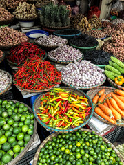 Fresh vegetables for sale at street food market in the old town of Hanoi, Vietnam. Garlic, Lemon, Ananas, Onions, Peper, Red chillies, carots