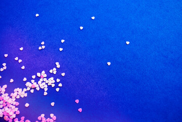 Small pink hearts on a blue background. Heart shaped sequins. Place for text and logo. Love and Valentine's Day concept.