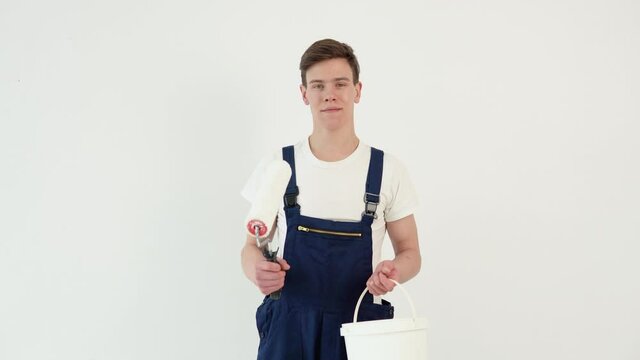 Painter with a roller in his hands looks at the camera