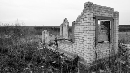 Destroyed and burnt brick structure with a window at the edge of the field