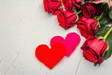 Fresh burgundy roses with felt hearts on a white putty background