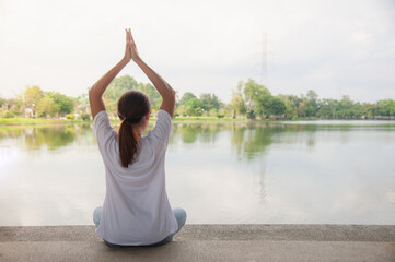 An Asian woman relaxing by the water in a park