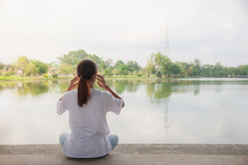 An Asian woman relaxing by the water in a park