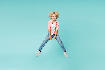 Fototapeta na wymiar Full length of laughing little kid boy 10s years old wearing casual pink shirt jumping spreading legs isolated on blue turquoise color background children studio portrait. Childhood lifestyle concept.