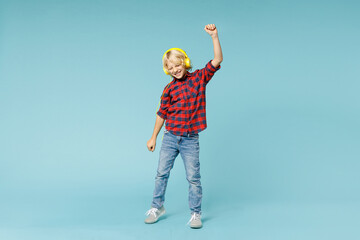 Full length of funny little kid boy 10s in red checkered shirt listen music with headphones dancing...
