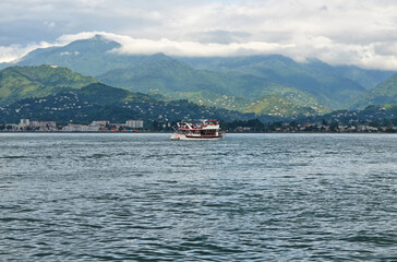 the boat sails on the sea with the mountains in the background
