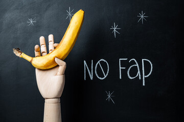 Inscription on chalkboard No fap and a hand holding a banana