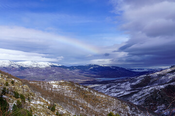 Mountain landscape with snow and rainbow on the horizon.

