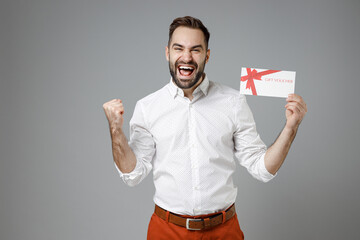 Happy joyful young bearded business man in classic white shirt standing hold gift certificate doing...