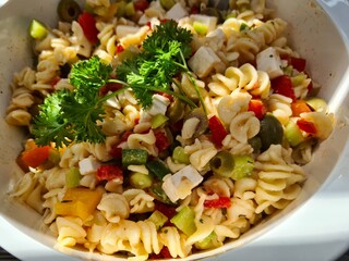 Close up of a pasta salad with green and red Italian seasonings.