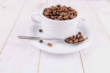 coffee beans in a white cup on a wooden table