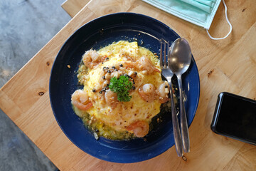 Top view shrimp fried rice with omelette topping on wood table