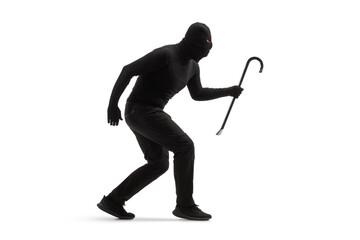 Full length shot of a burglar in black clothes with a balaclava and a crowbar walking slowly - obrazy, fototapety, plakaty
