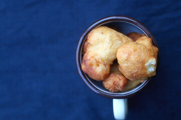 Bowl of Croatian fritters, traditional snack made with sweet fried dough. Top view, dark blue background.