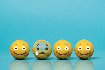 Wooden balls as emoticons. Concept of difference between sadness and happiness
