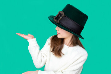 A closeup portrait of preteen girl in St. Patrick's Day hat on green backgroundwhite. Copy space