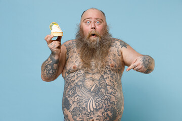 Shocked fat pudge obese chubby overweight man has tattooed big belly hold sweet pastries cake...