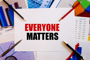 The word EVERYONE MATTERS is written on a white background near colored graphs, pens and pencils....