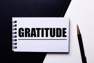 The word GRATITUDE written in red on a black and white background near the pen
