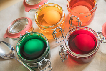 Gekochte Eier färben in Kaltfarben in Rot, Orange, Gelb, Grün in Glas auf Papier Unterlage in Küche zu Ostern