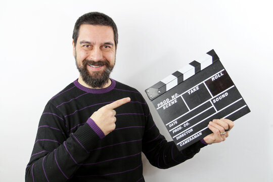 Bearded man holding clapperboard smiling happy  on white backgrond pointing with hand and fingers