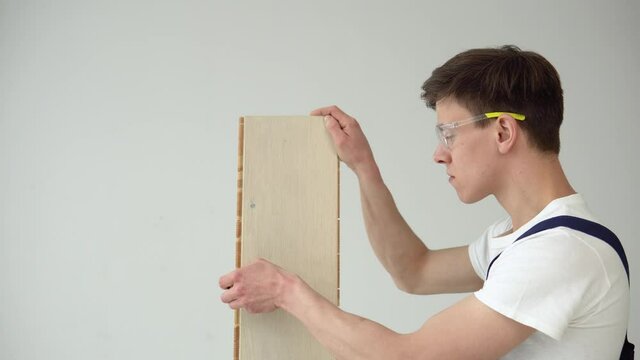 The floor installer holds a parquet or vinyl board and installs the flooring