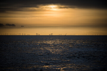 Naklejka na ściany i meble Offshore wind farm across the water at dusk 