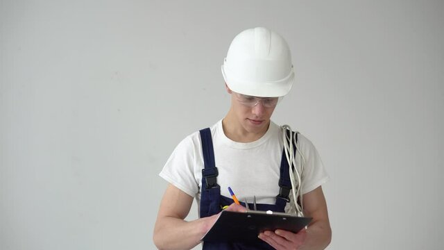 Master or assistant makes notes on a white wall background during repairs in the house