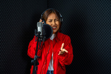 Asian woman singer wearing red shirt rehearsal musical performance in recording studio with microphone 