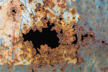 Old steel tank is holes from rust close up.