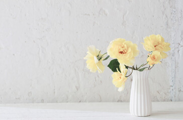 yellow roses in white vase on background white wall