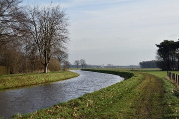 Peaceful canal in the Netherlands countryside with trees on the riverbank