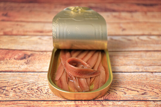 Open can of Cantabrian anchovies (Santo&ntilde;a anchovies) on wooden table with blur and blank space