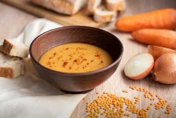 Hot vegetarian red lentil cream soup with ingredients.