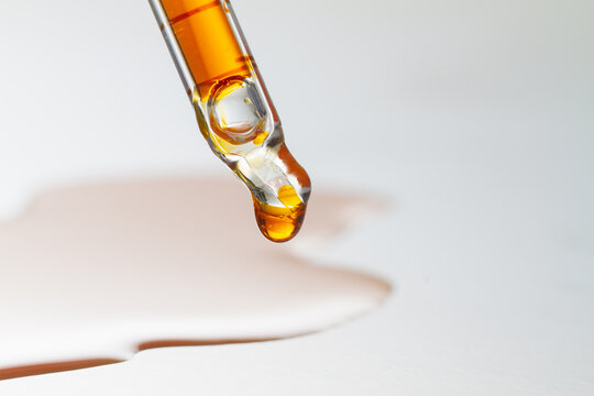 A Drop Of Orange Oil On The Tip Of A Glass Pipette.