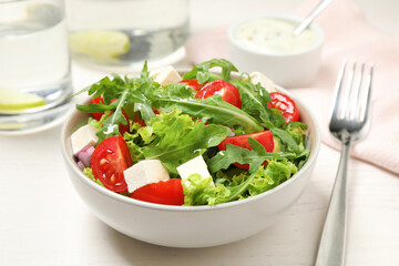 Delicious salad with arugula and vegetables on white table, closeup