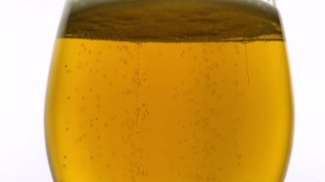 Lager beer glass with bubbles filmed in slow motion in close up.Detailed video clip of beer pint glass eing filled with golden lager alcoholic drink in slow mo.Enjoy fresh beer wtih foam in pub