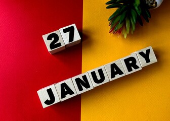 January 27  in black letters on wooden blocks on a divided yellow-red background .Next to a flower .Calendar for January.
