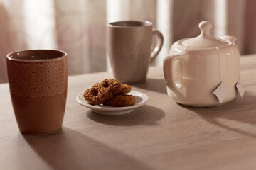Biscuits, cups and teapot on the table.
