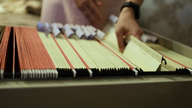 young woman goes through documents in home archive, looking for the right folder, concept family genealogy, memories, generational ties, museum historical materials